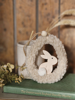 Boucle shaped egg easter hanging decoration with wooden bunny inside. Pale cream colour.