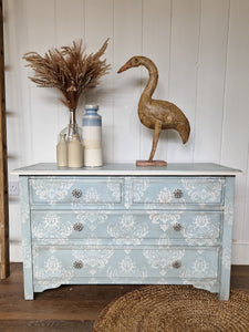 fleur de lis hand painted chest of drawers in soft blue and white colours fished off with faux bone flower shaped handles.