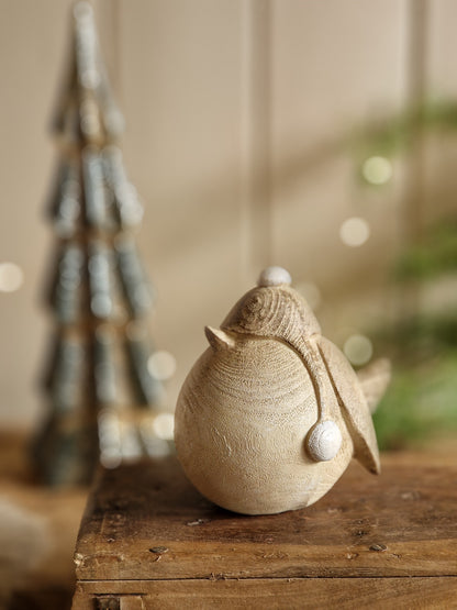 A close-up of a decorative ceramic owl figurine with white bead eyes, mounted on a rustic wooden post against a softly blurred beige background.